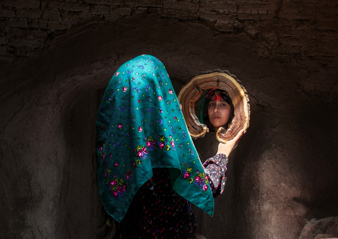 A person in a cave-like space looking into a carved mirror.