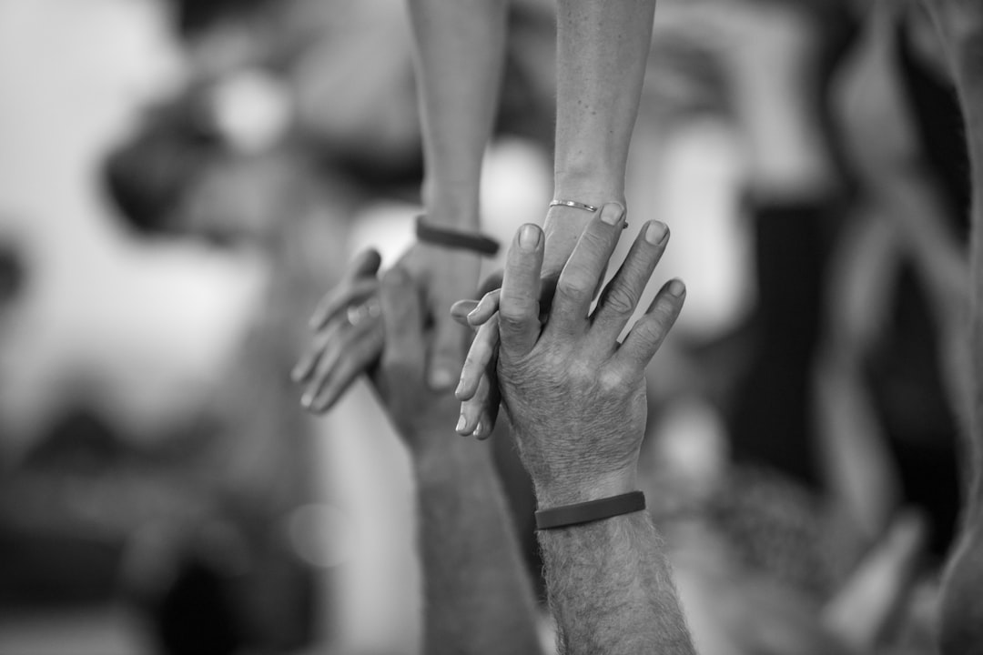 A monochrome close-up of hands reaching toward each other.